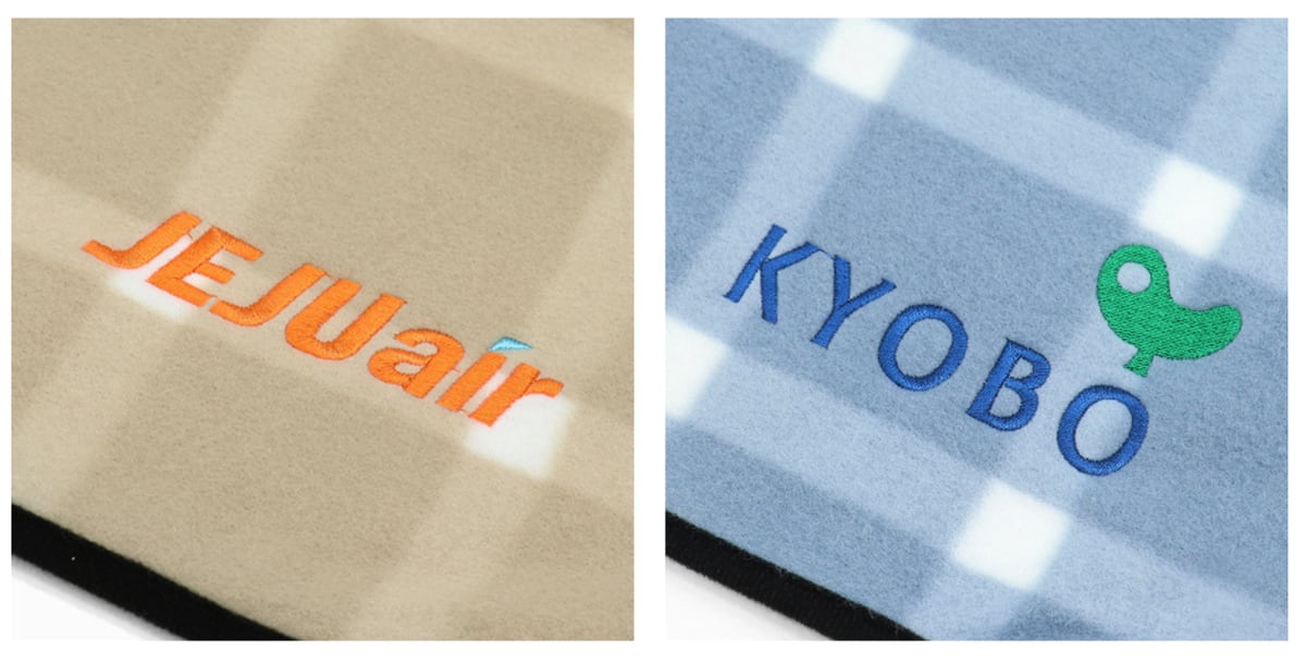 베이지 체크 담요에 주황색 「JEJUair」, 하늘색 체크 담요에 파란 「KYOBO」 글자와 초록 새 로고를 자수로 놓은 모습