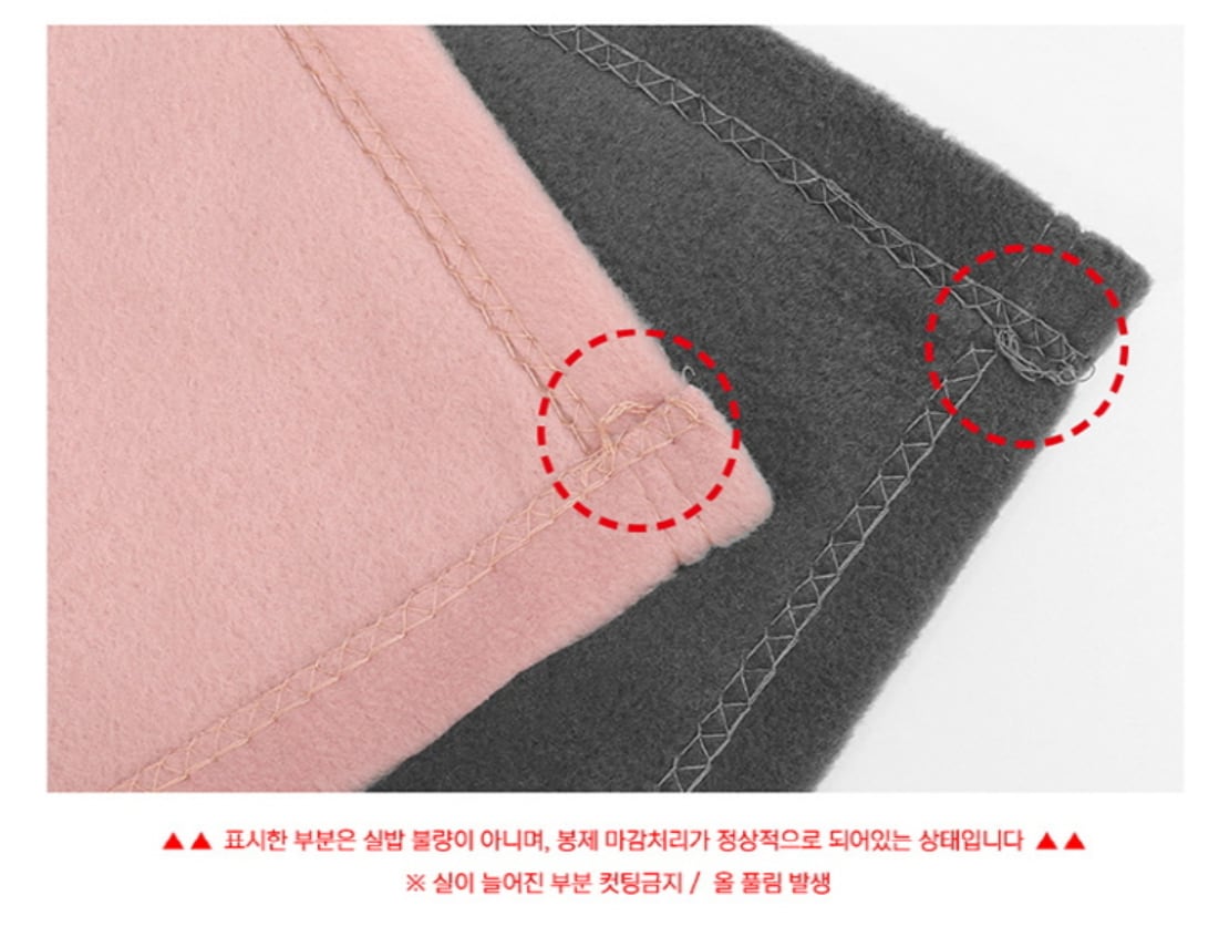 분홍·회색 플리스 담요 모서리의 박음질 끝부분에 실이 조금 늘어져 있는 모습을 빨간 점선으로 표시 — 실밥 불량이 아니라 봉제 마감이 정상으로 된 상태이며, 늘어진 실을 자르면 올이 풀립니다