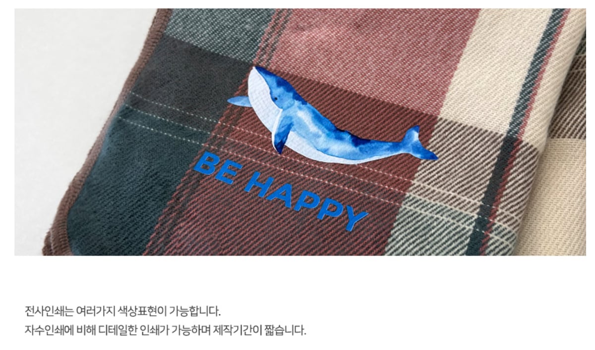 체크무늬 담요 모서리에 파란 고래 그림과 「BE HAPPY」 글자를 컬러 전사로 붙인 모습