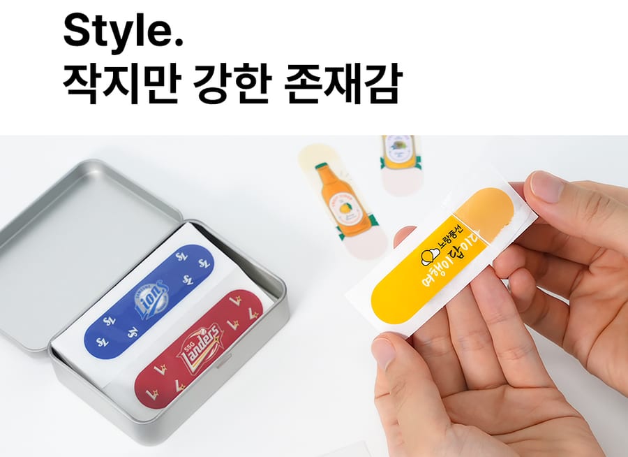 은색 틴케이스에 파랑·빨강 밴드가 담겨 있고, 손으로 노란 밴드를 꺼내 드는 모습 — 「Style. 작지만 강한 존재감」